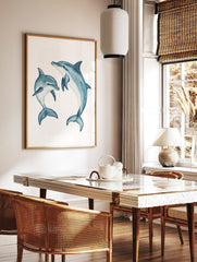 Two blue watercolour dolphins, one large and one small, in dynamic swimming poses on a white, in a styled room mockup