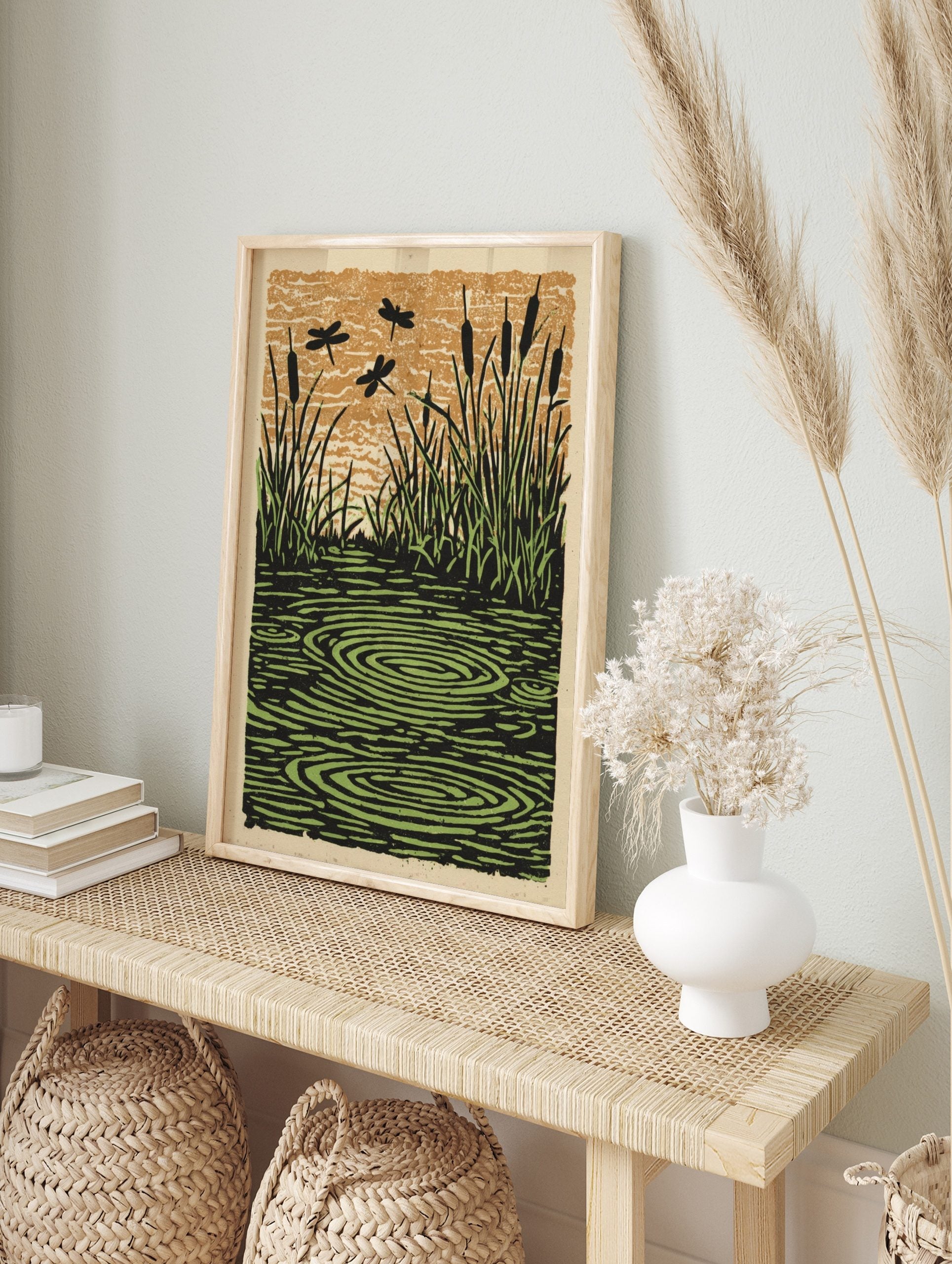 Illustrative print of dragonflies flying over a pond with cattails, grass, and water ripples, in an alternate framed mockup