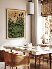 Illustrative print of dragonflies flying over a pond with cattails, grass, and water ripples in, in a styled room mockup