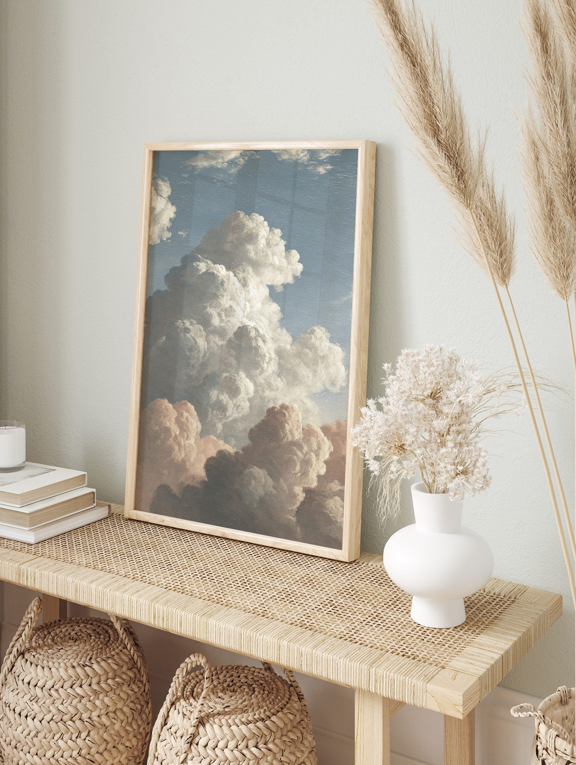 Classical painting of dramatic cumulus clouds in white, grey, and peach against a blue sky, in an alternate framed mockup
