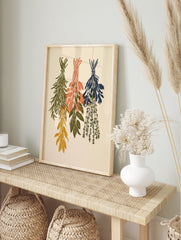 Three bundles of dried herbs in sage green, peach, and navy hanging as a botanical, in an alternate framed mockup