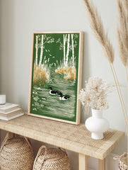 Illustrative print of two ducks swimming in a green pond framed by white birch trees and reeds, in an alternate framed mockup