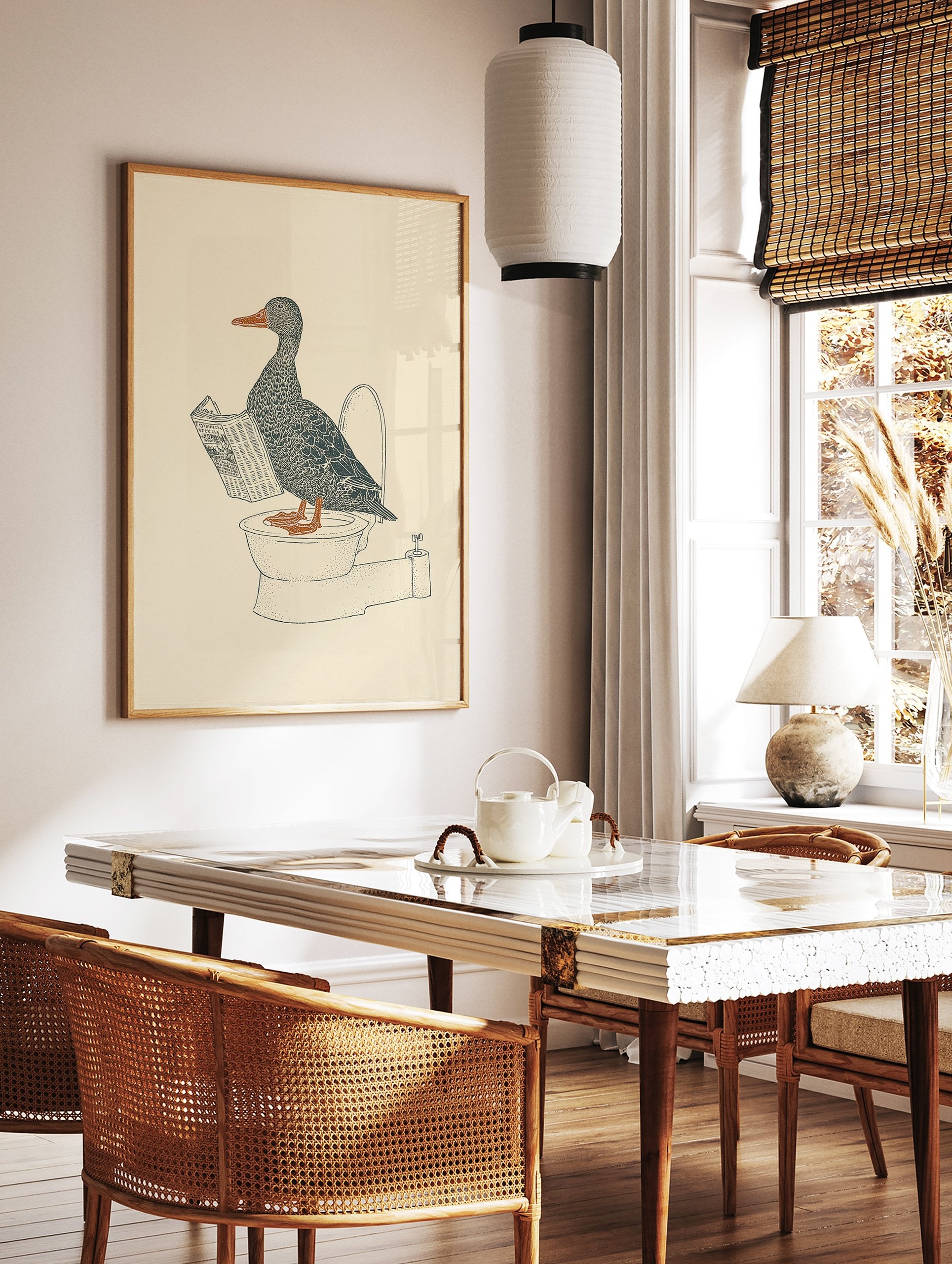 Duck wall art illustration of a gray duck with an orange beak and feet reading a newspaper while sitting on a toilet. - Image 2