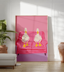 Two white ducks with yellow beaks and feet sitting on a pink couch, illustrated wall art print against a pink background. - Image 3
