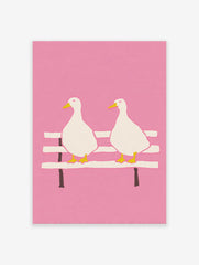 Illustrated pink duck wall art featuring two white ducks with yellow beaks and feet sitting on a bench against a pink background.