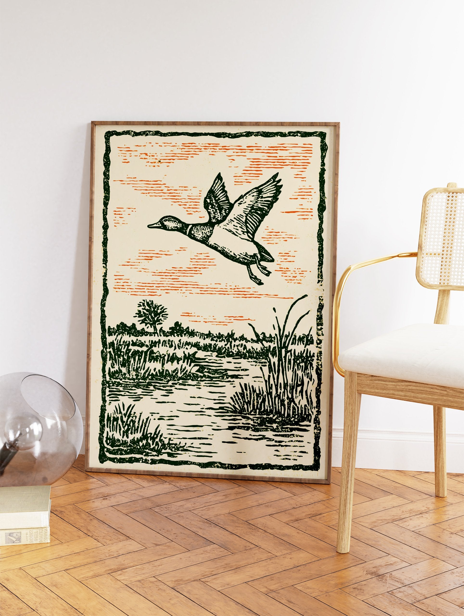 Vintage illustration of a duck flying over a green marshland with an orange sky, framed by a dark green border. - Image 2