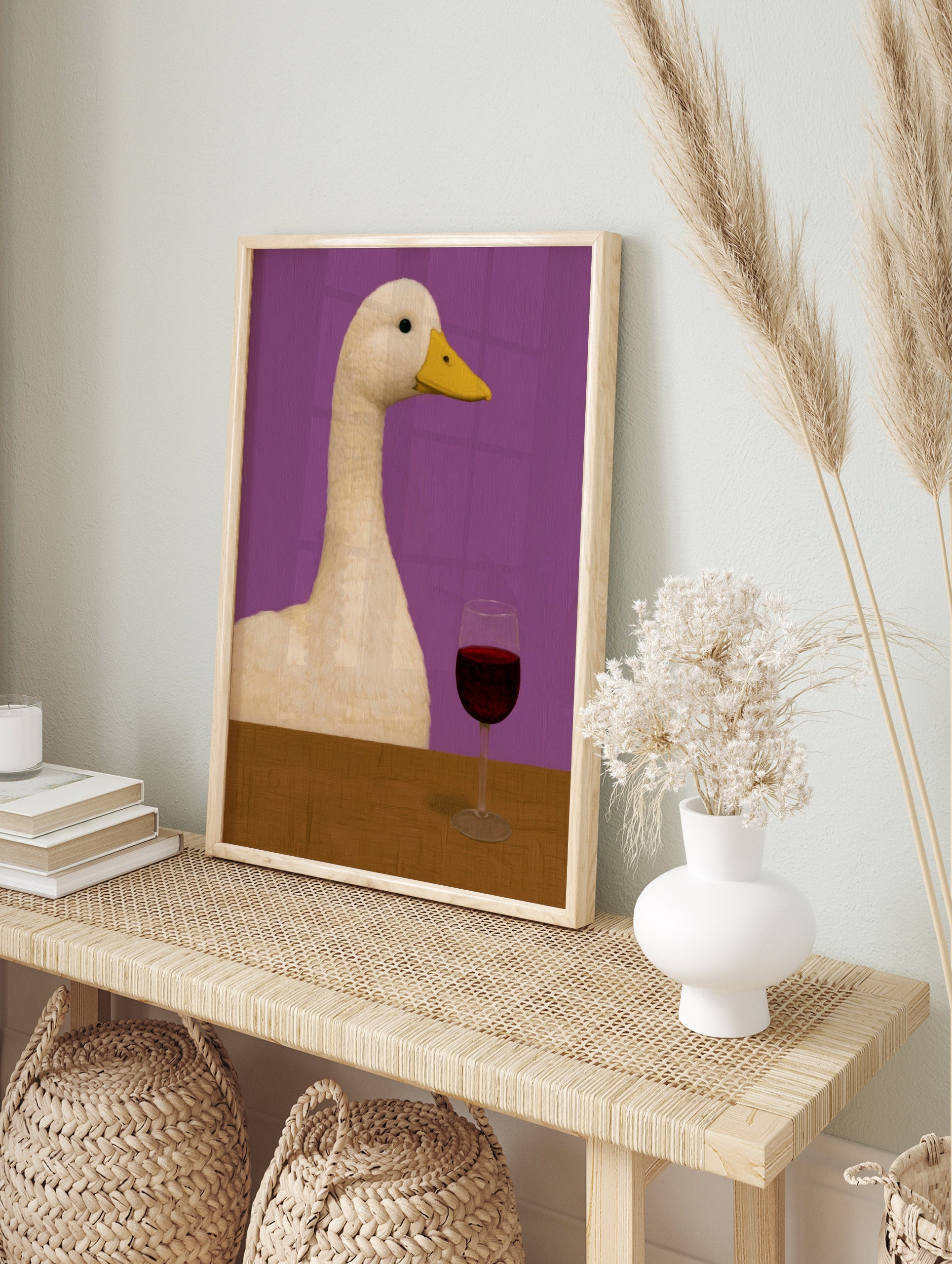 Quirky illustration of a white duck sitting at a wooden table with a glass of red wine, in an alternate framed mockup