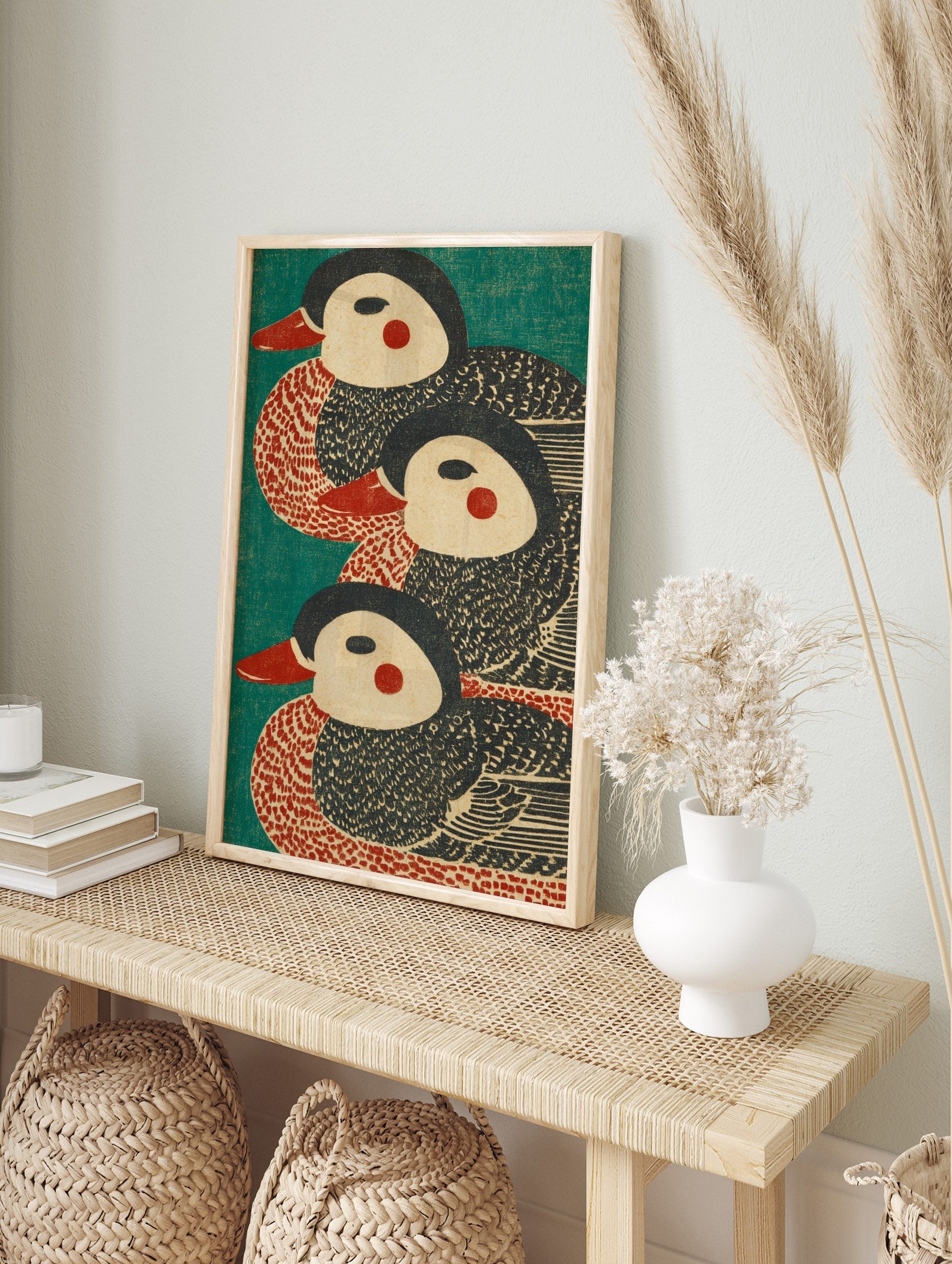 Three stylised duck illustrations with red beaks and cheeks on a teal background, in a, in an alternate framed mockup