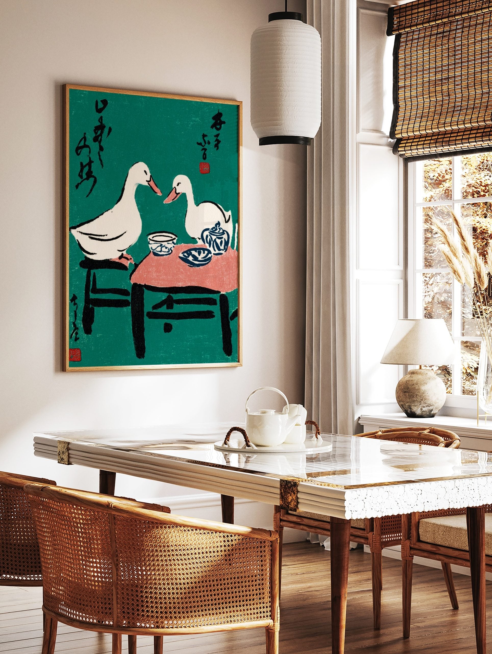 Illustrative print of two white ducks at a tea party with blue pottery, black text, and red seals, in a styled room mockup