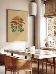 Illustrative botanical print of a cluster of orange-brown mushrooms with green leaves on a beige, in a styled room mockup