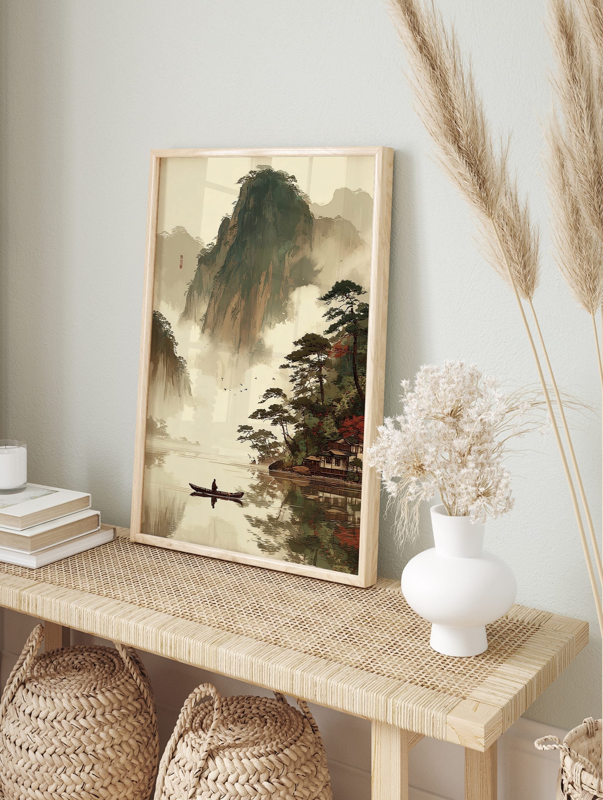East Asian landscape art print with misty mountains, lake, person in boat, pine trees, and, in an alternate framed mockup