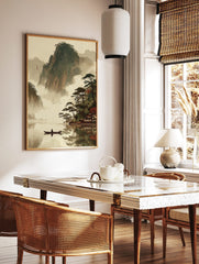East Asian landscape art print with misty mountains, lake, person in boat, pine trees, and, in a styled room mockup