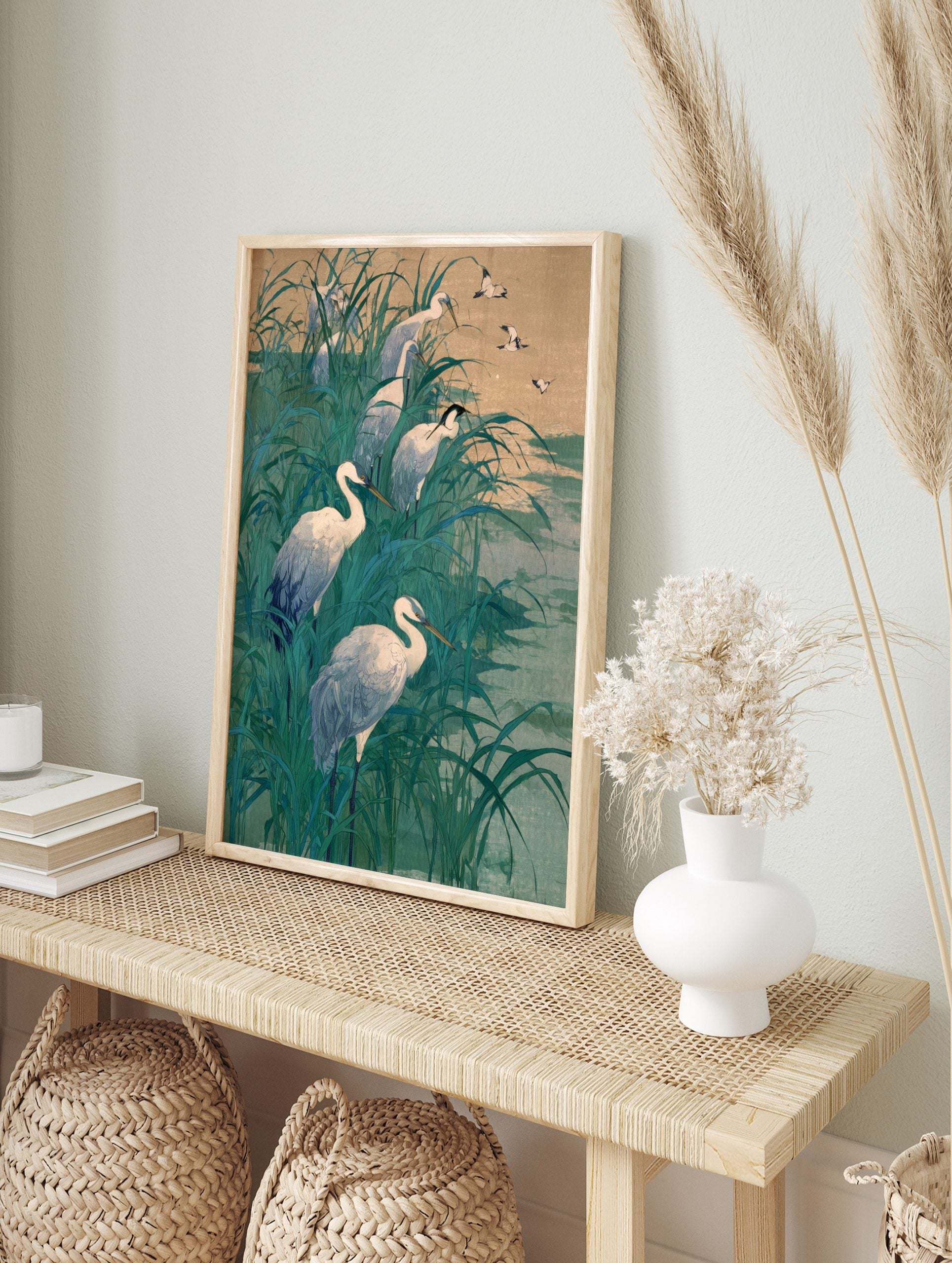 White egrets wading and flying in tall teal marsh grass with a muted sky and water, in an alternate framed mockup