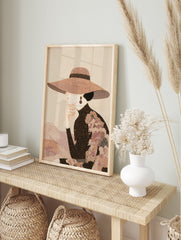 Elegant woman in profile wearing a wide-brimmed patterned hat and high-necked top, hand to, in an alternate framed mockup