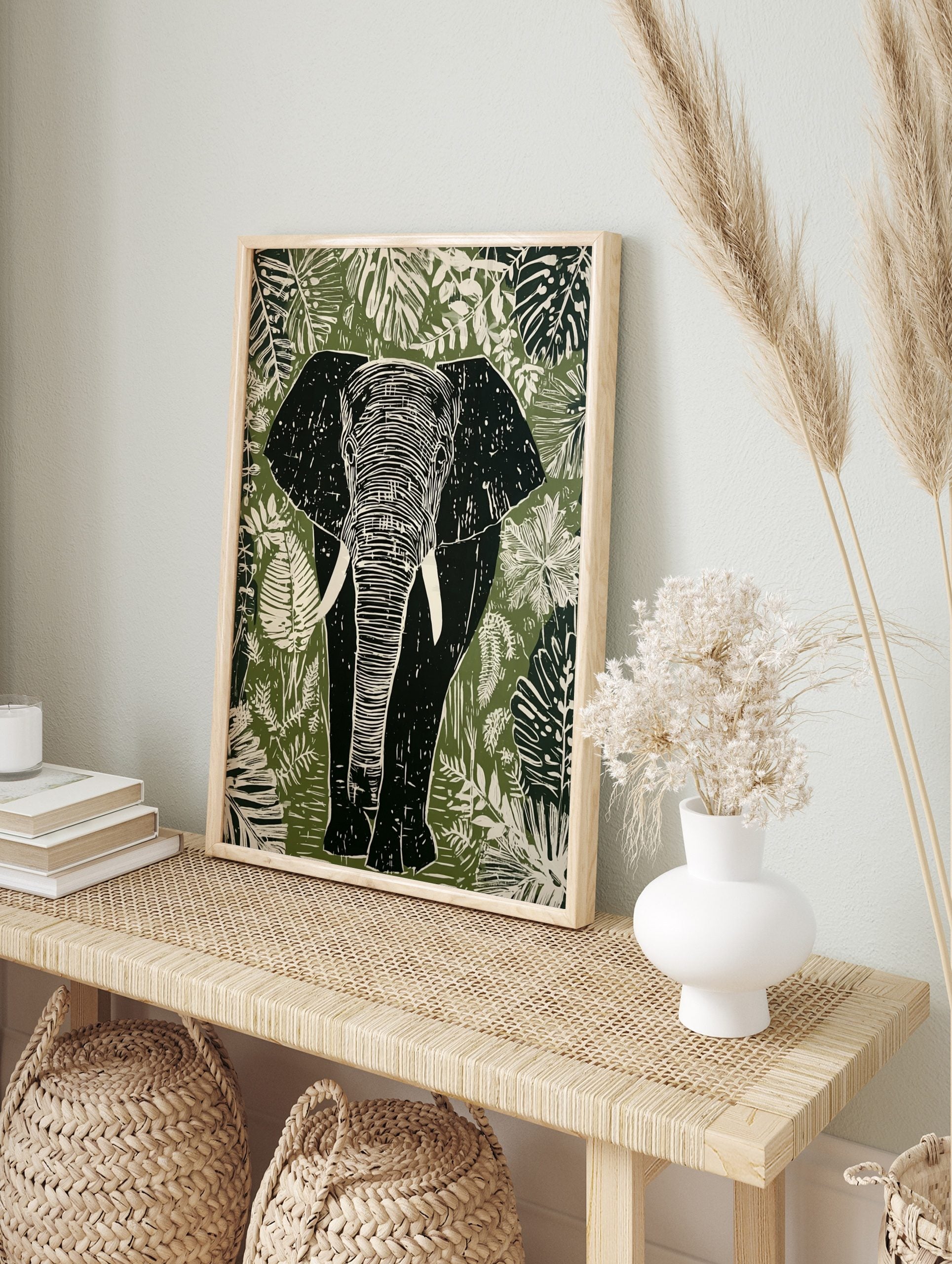 Linocut style elephant wall art print with tropical leaves in green, white, and black tones, in an alternate framed mockup