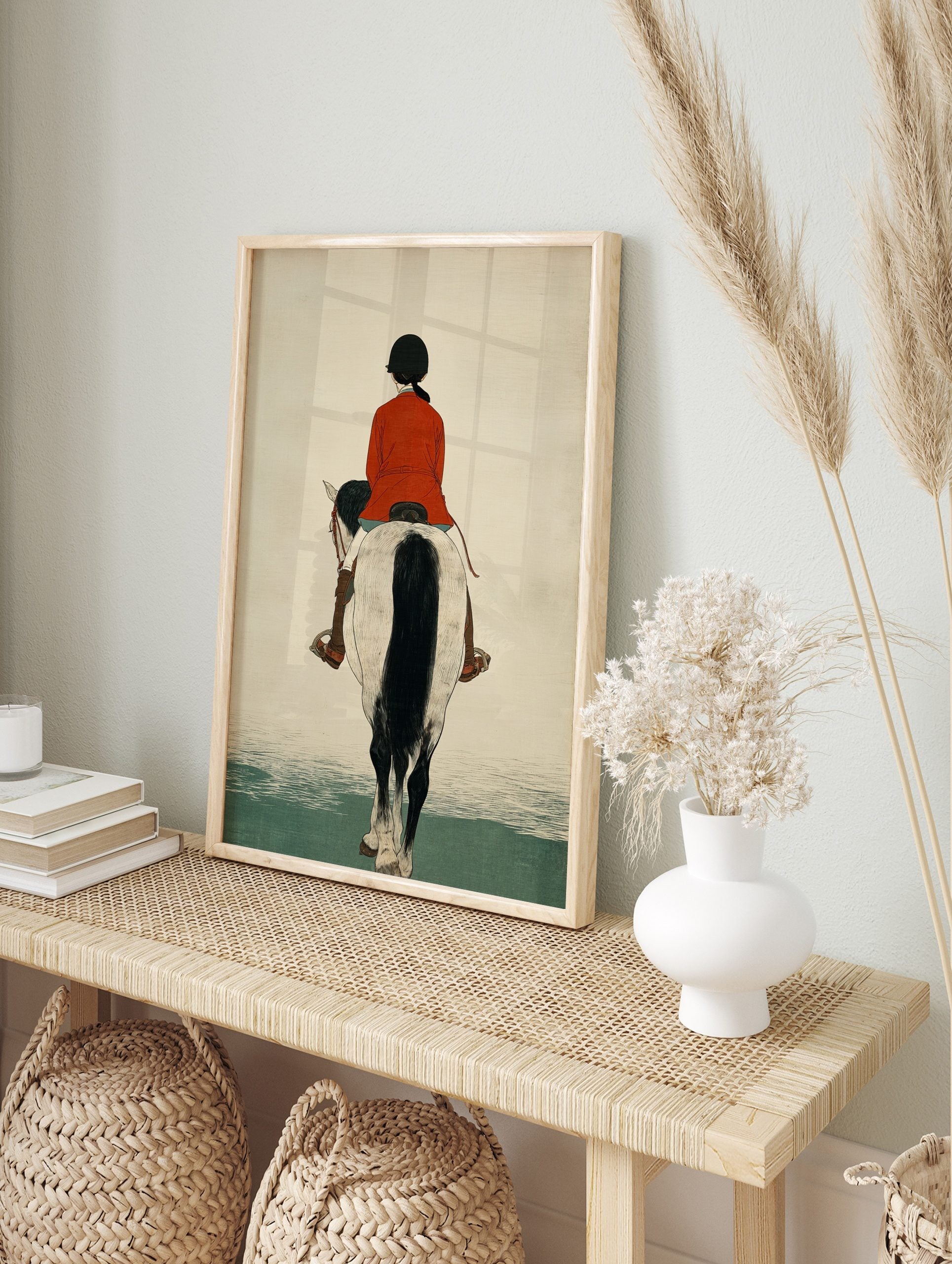 Illustrative print of a horse rider in a red jacket on a white and black horse, viewed from, in an alternate framed mockup