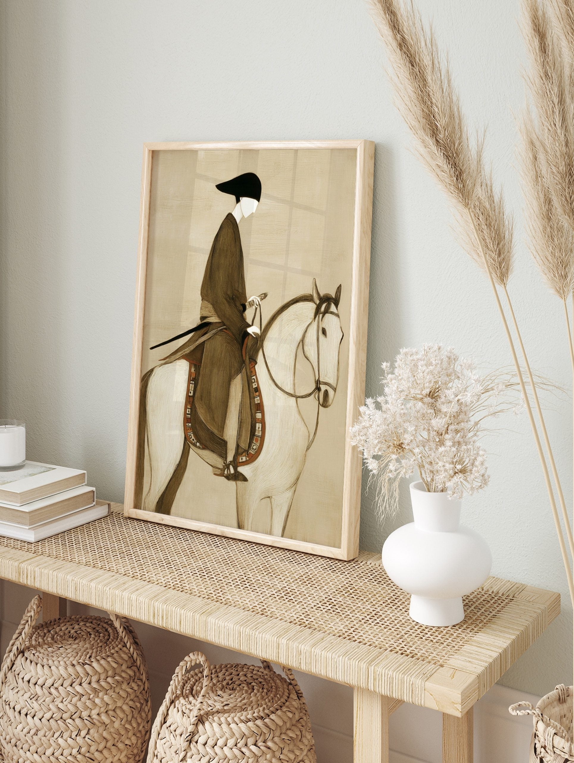 Illustrative print of a stylised figure in dark robe and black hat riding a white horse with, in an alternate framed mockup