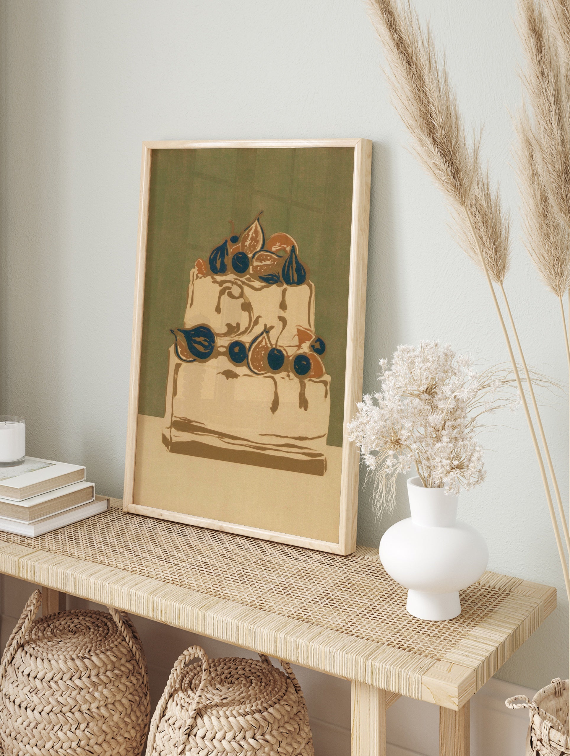 Illustrative wall art print of a two-tiered cake decorated with figs and blueberries against, in an alternate framed mockup