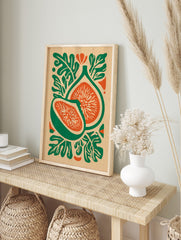 Botanical illustration of two fig fruit halves with green skin, orange flesh, and stylised, in an alternate framed mockup