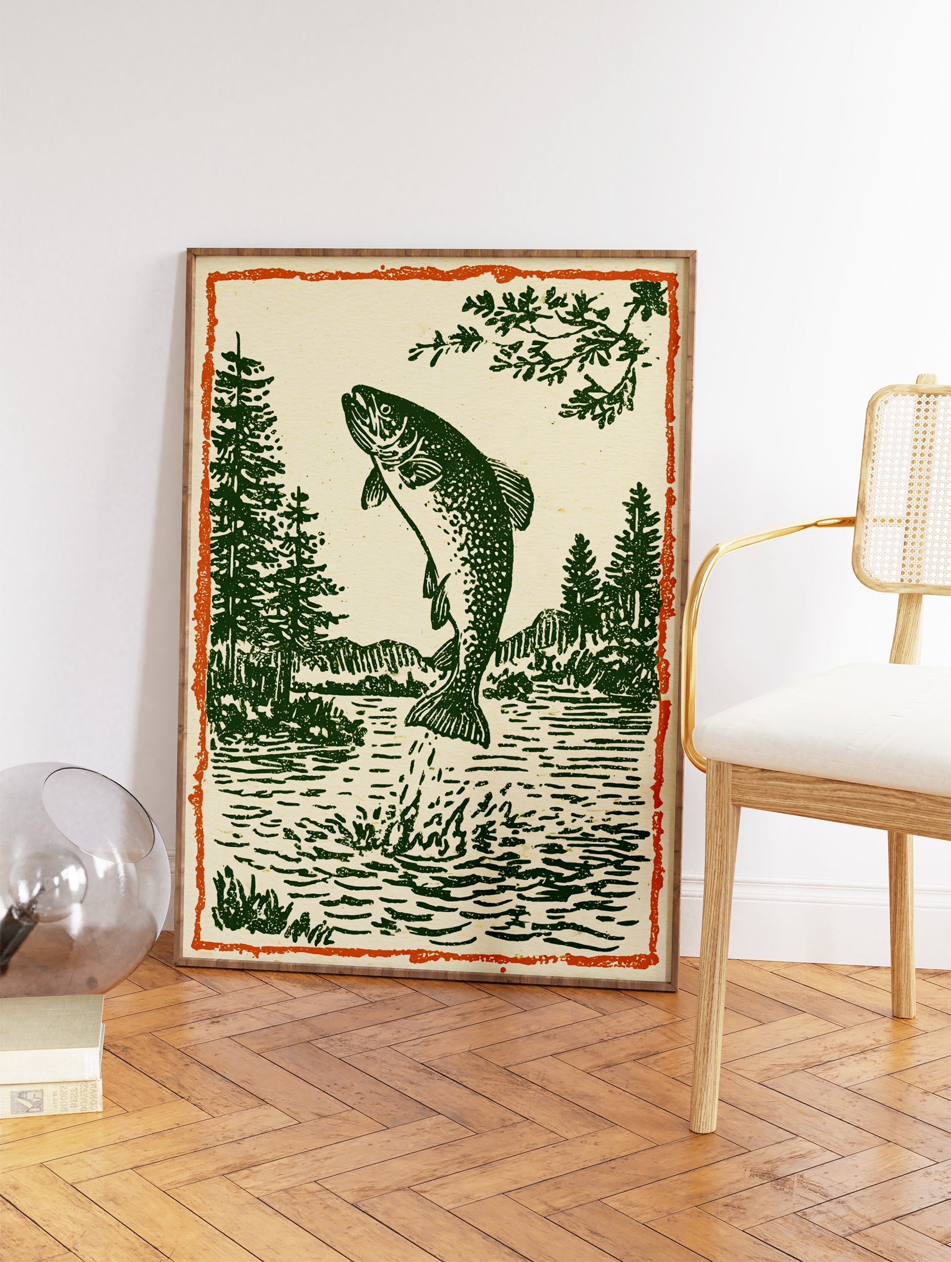 Woodcut style illustration of a jumping trout fish in a lake with pine trees and mountains, framed by an orange border. - Image 2