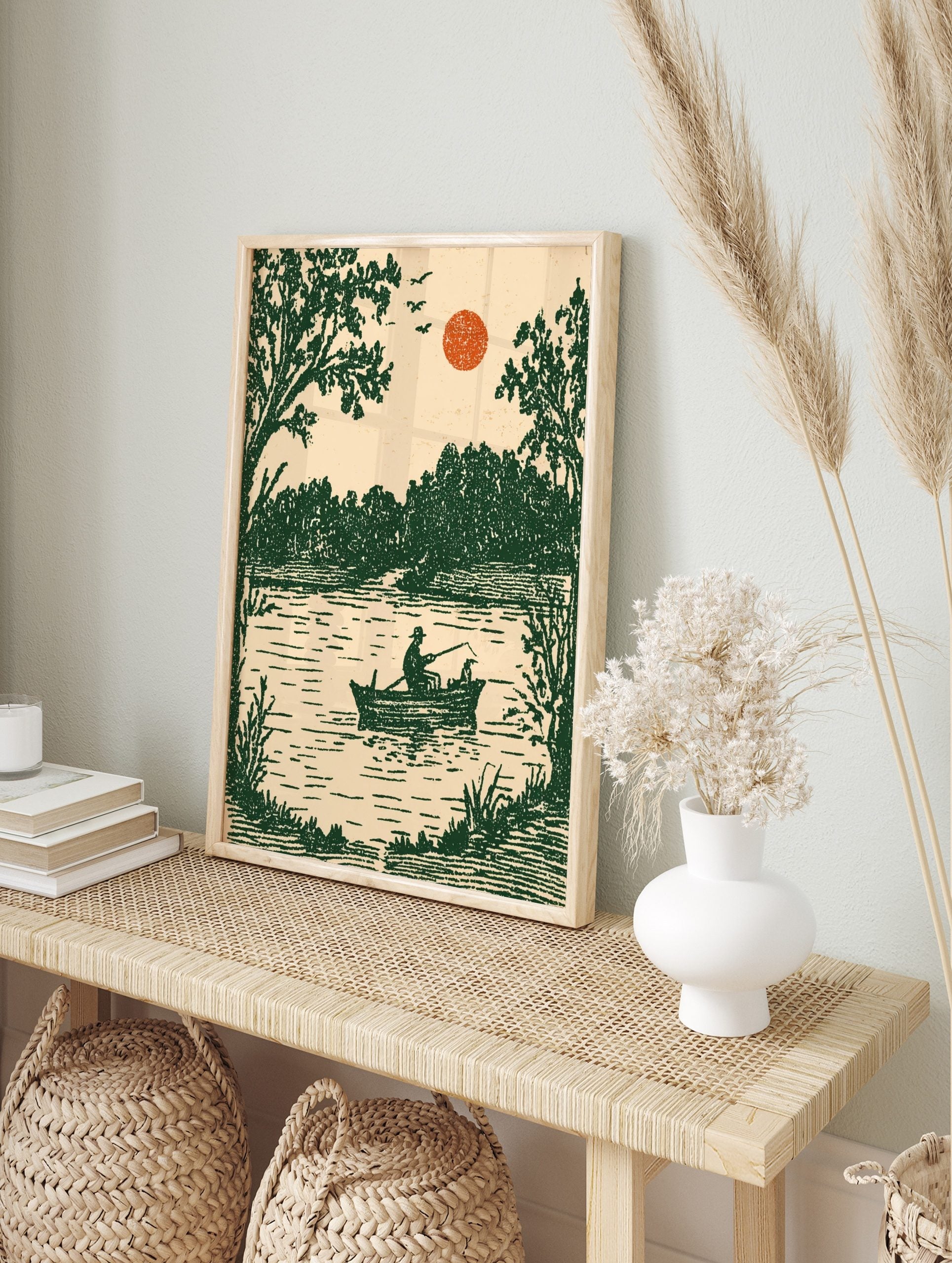 Vintage illustrative art print of a fisherman and dog in a boat on a lake with green trees, in an alternate framed mockup