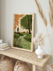 Woodcut style print of a fisherman by a stream with a large weeping willow tree and orange sky, in an alternate framed mockup