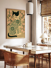 Stylized cat illustration with green floral patterns and pink flowers on a tan background, in a styled room mockup