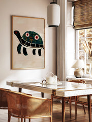 Illustrative dark green turtle wall art print with floral decorated shell and red eyes on beige, in a styled room mockup