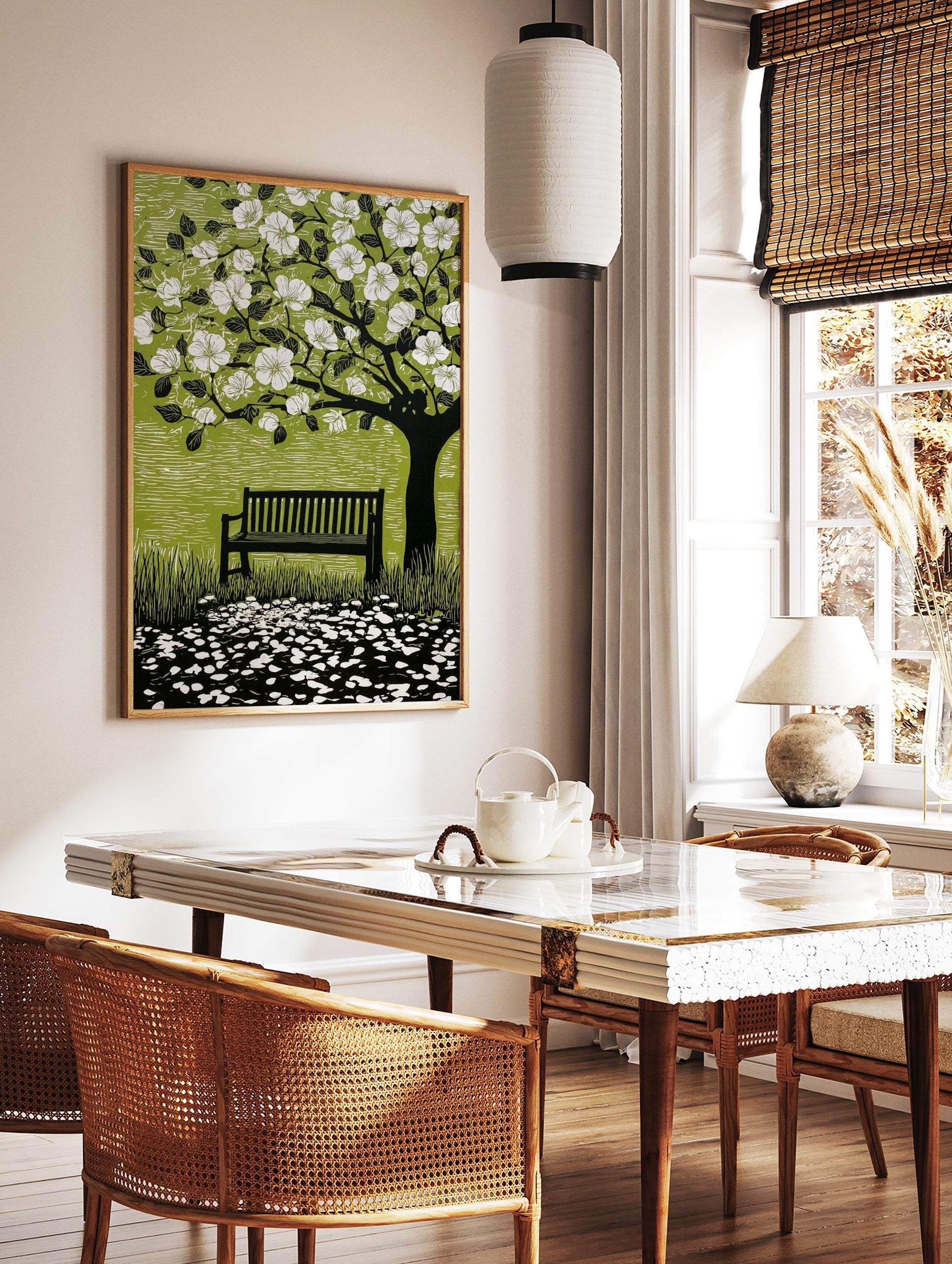 Linocut style print of a flowering tree with white blossoms, a dark bench, and scattered petals on, in a styled room mockup