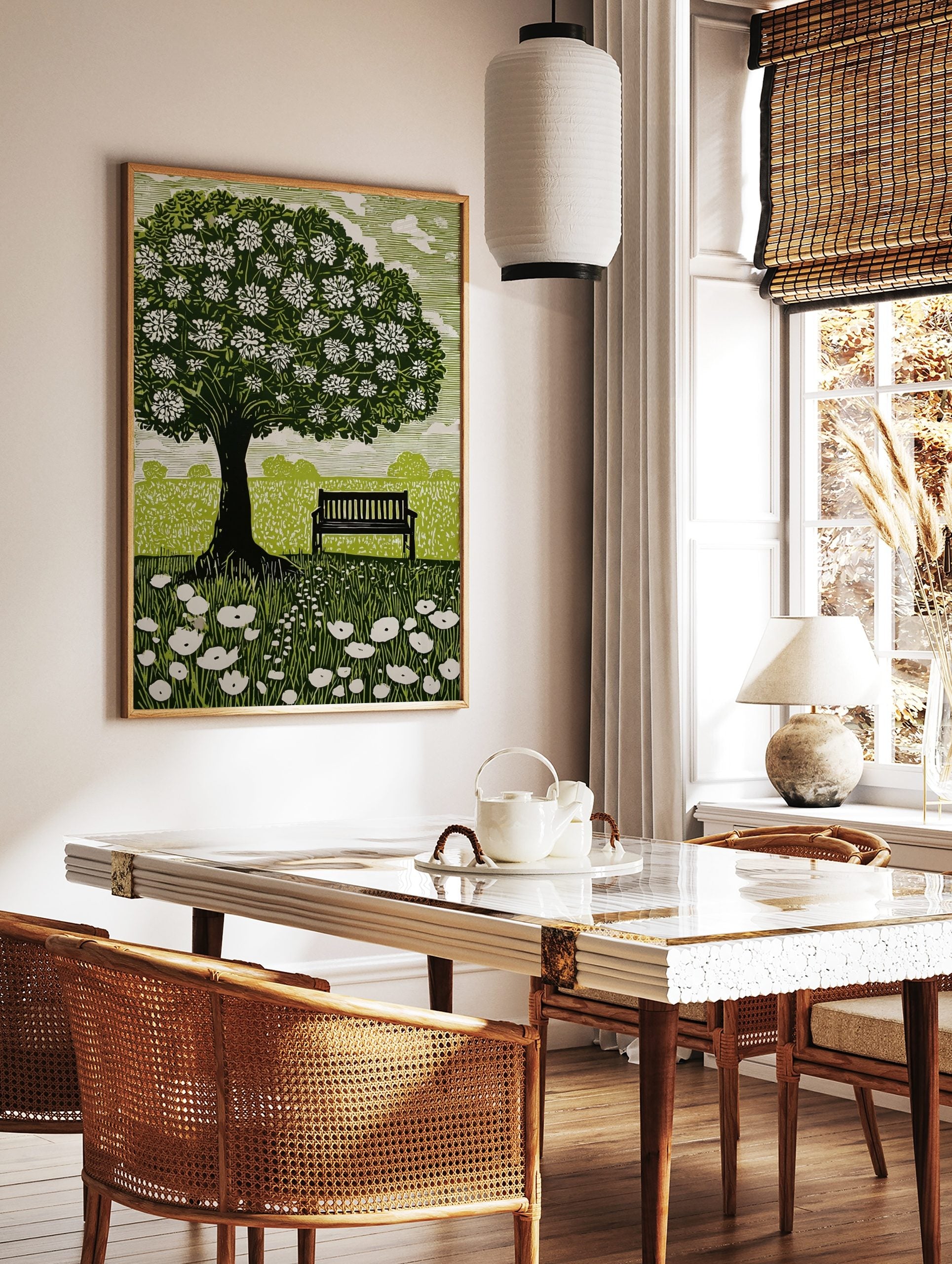 Linocut style print of a flowering tree, park bench, and wildflowers in a green field with white sky, in a styled room mockup