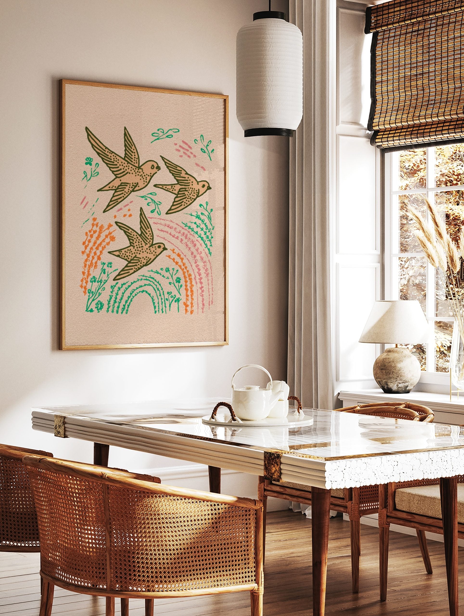 Illustrative print of three flying swallows with green leaves, orange plants, and pink streaks on, in a styled room mockup