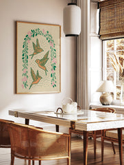 Three orange flying birds within an arched wreath of green leaves and pink flowers on a beige, in a styled room mockup