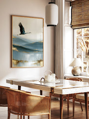 A crane in flight over abstract blue hills with golden accents, an artistic wall art print on paper, in a styled room mockup