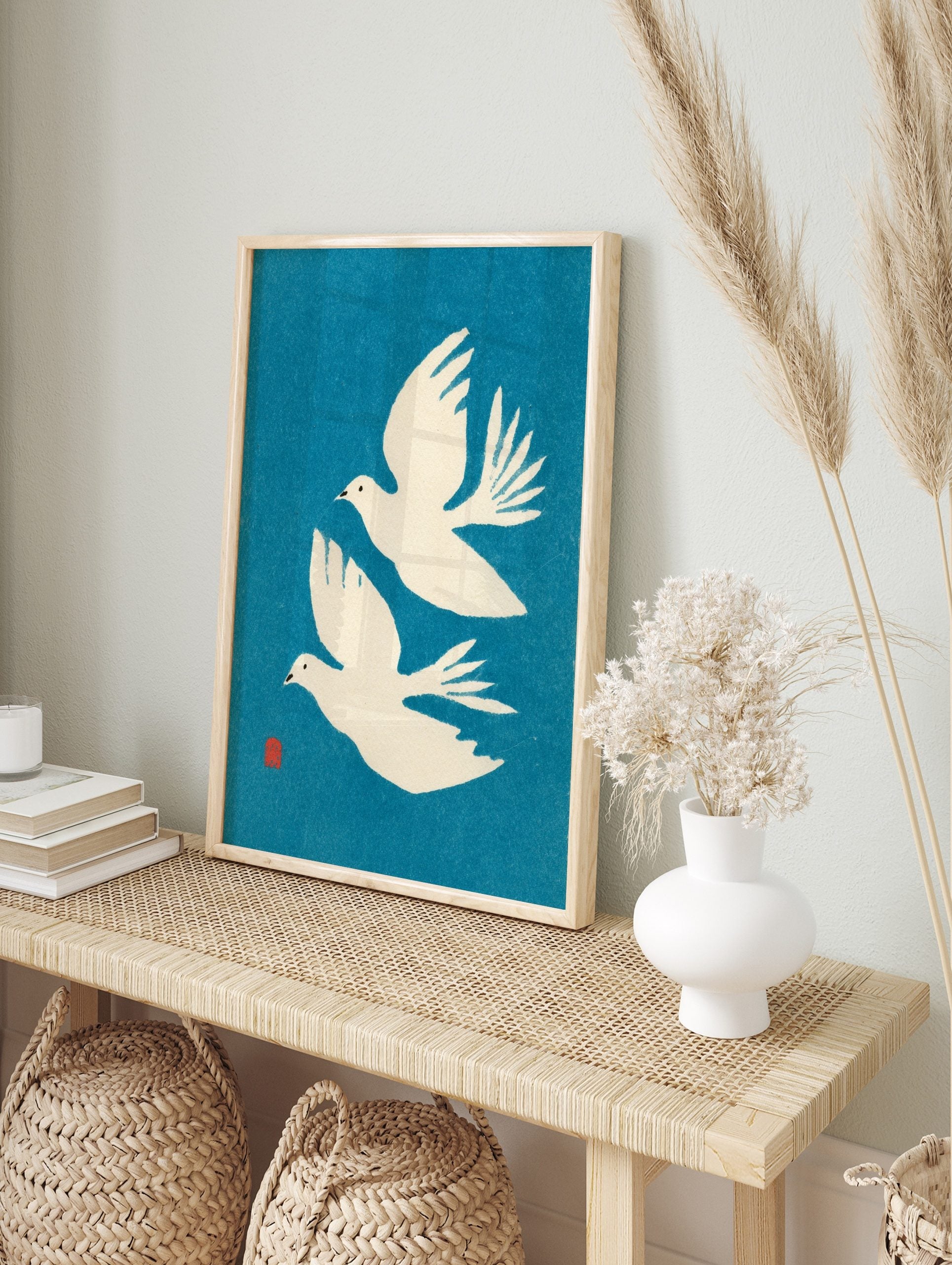 Two white flying doves minimalist art print on a vibrant blue background with a red artist's, in an alternate framed mockup