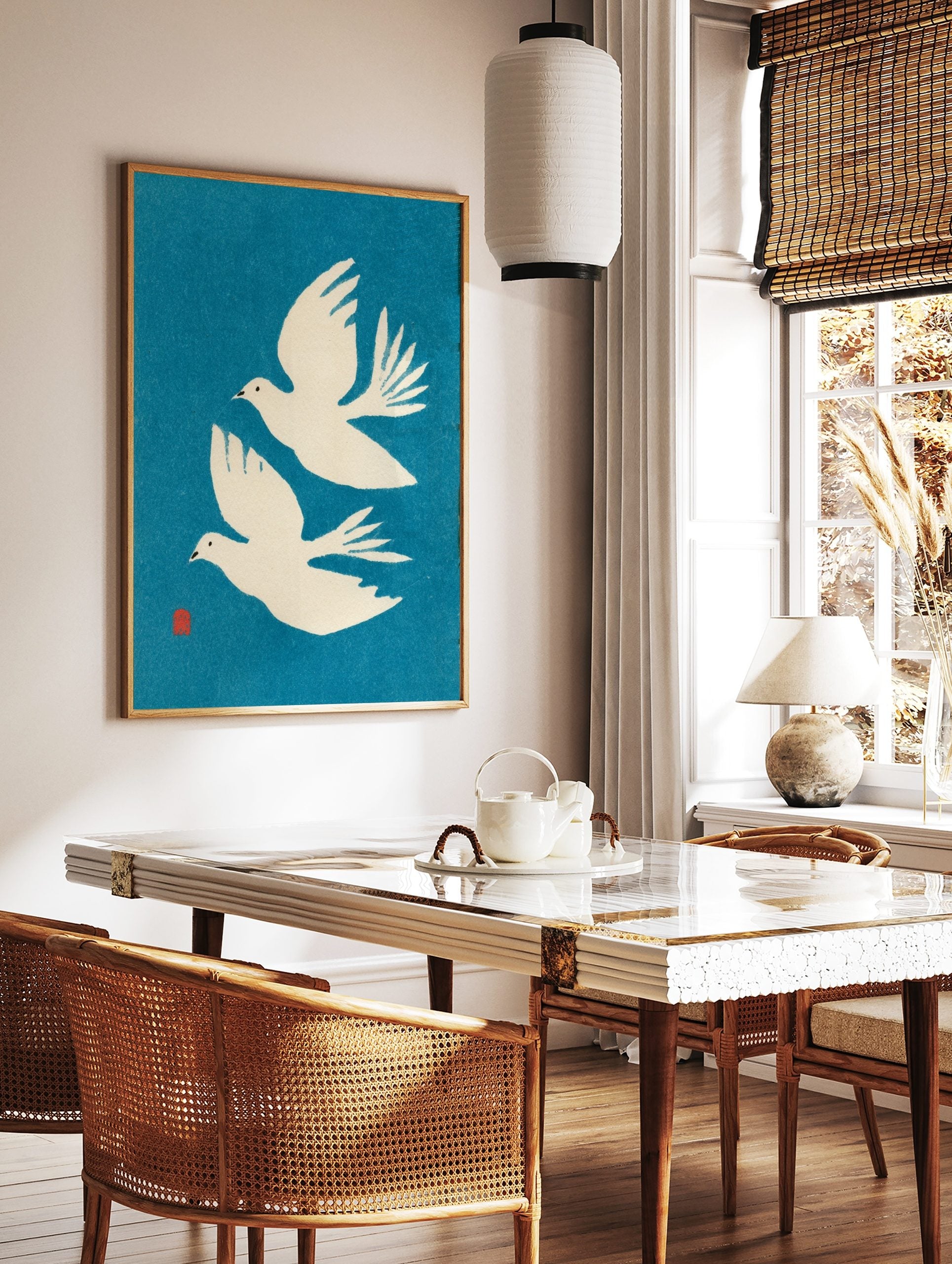 Two white flying doves minimalist art print on a vibrant blue background with a red artist's seal, in a styled room mockup