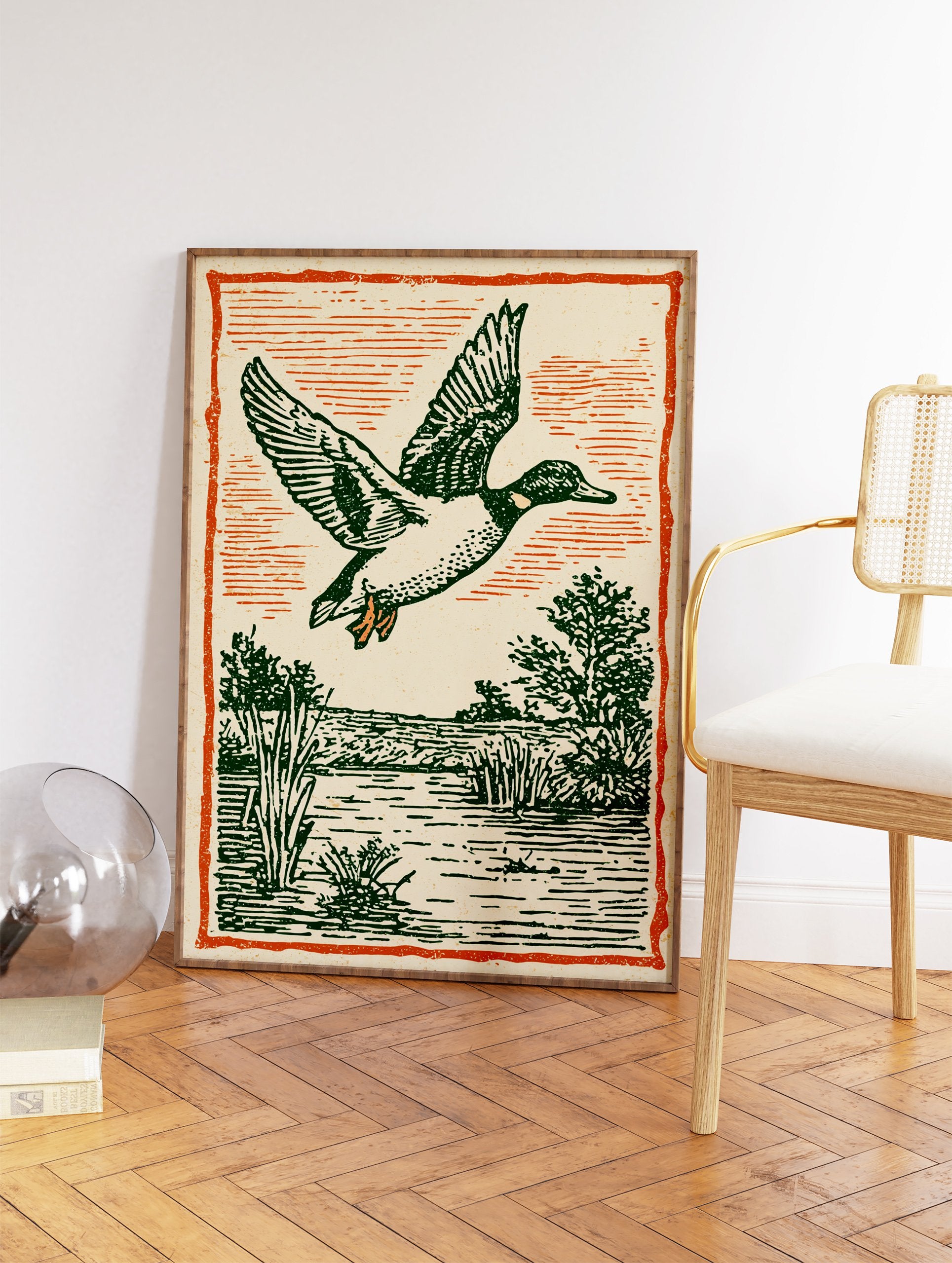 Vintage illustration of a flying duck with green feathers over a marsh and water, framed by an orange border. - Image 2