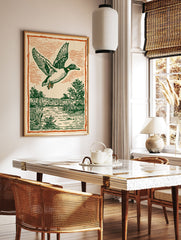 Vintage illustration of a flying duck with green feathers over a marsh and water, framed by an orange border. - Image 3