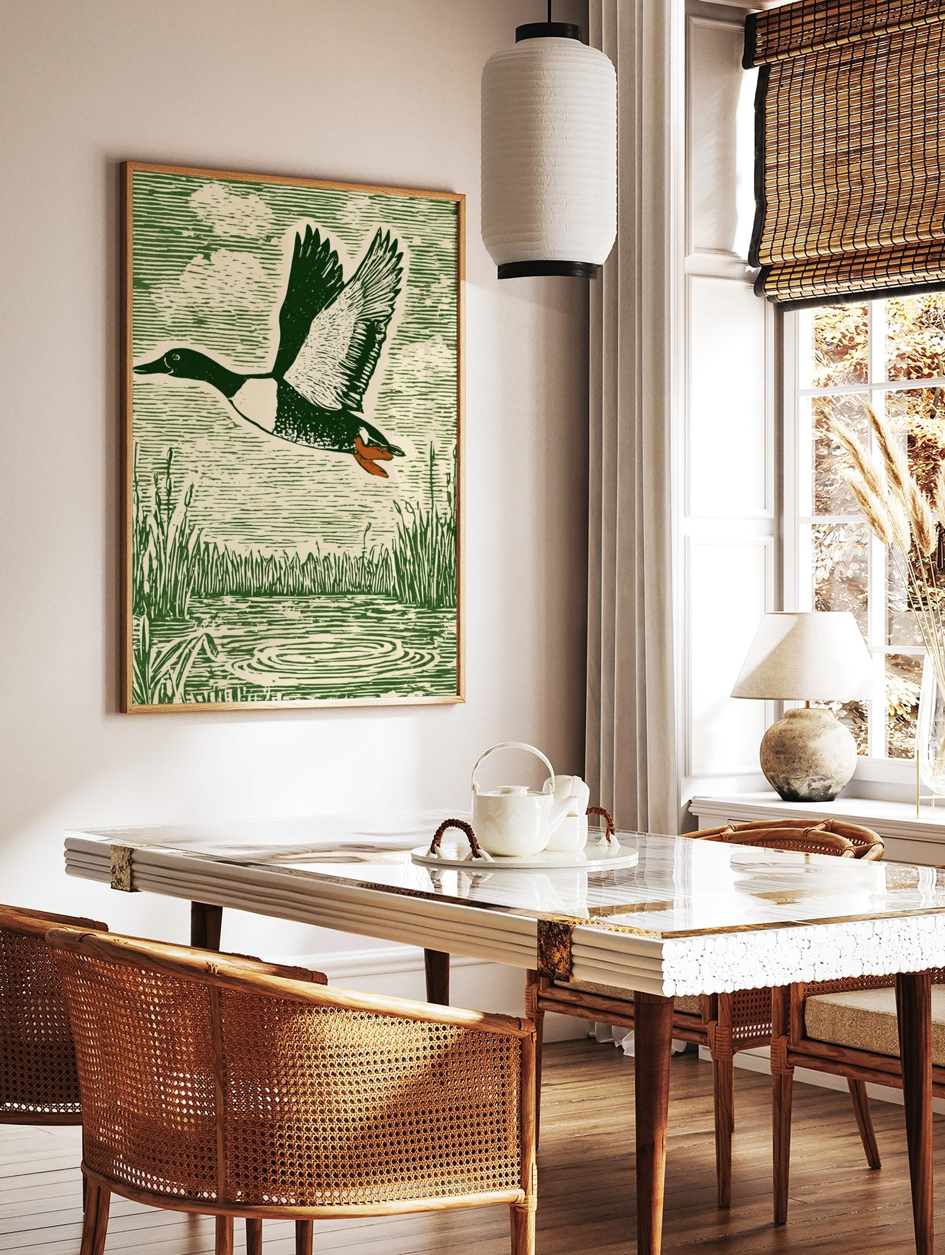 Green woodcut-style print of a flying duck with spread wings over water and reeds, in a styled room mockup