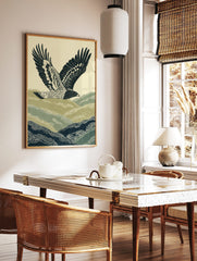 Illustrative print of a hawk flying over green and navy rolling hills against a pale sky, in a styled room mockup