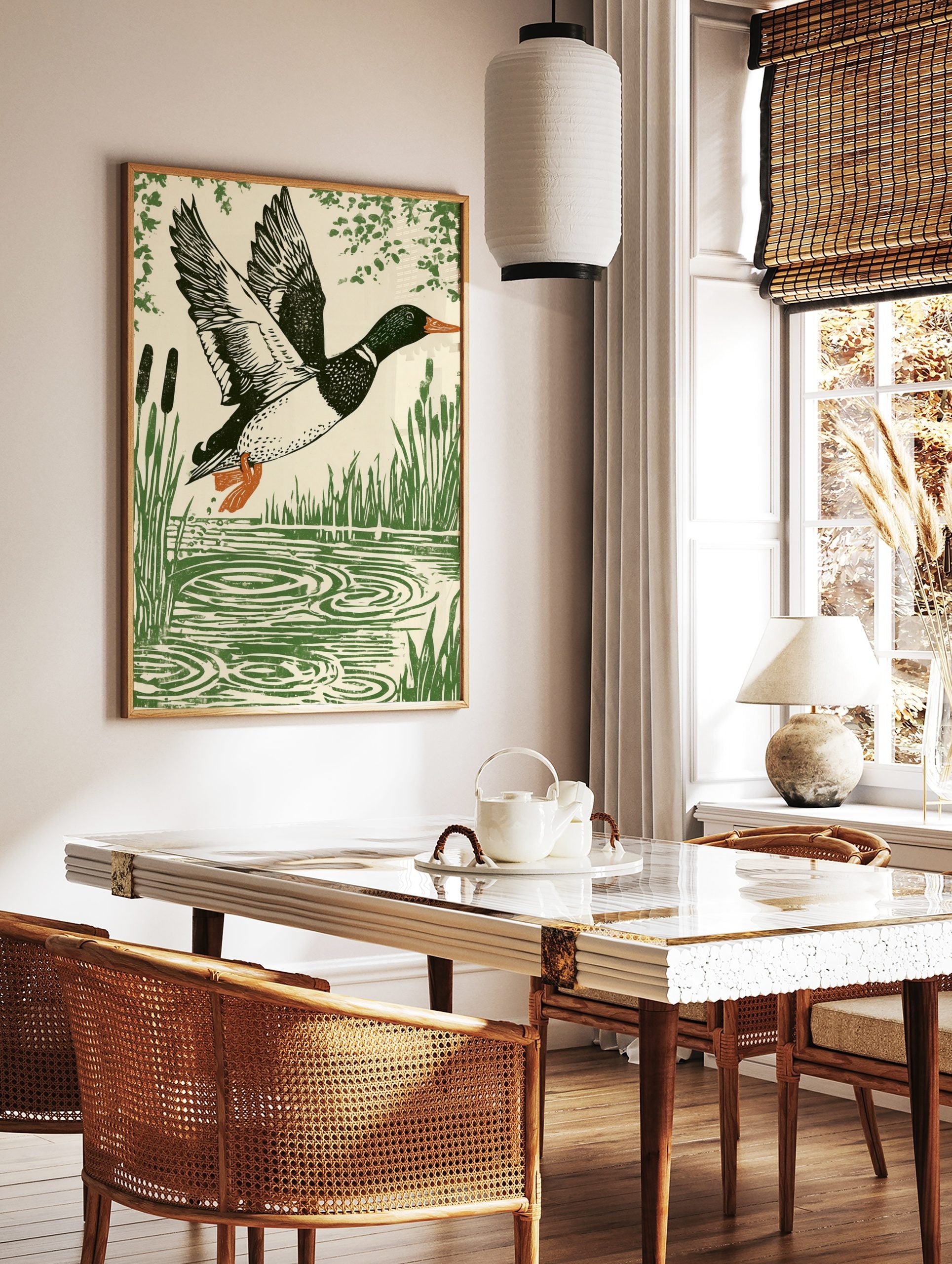 Linocut style print of a mallard duck in flight over water with reeds and foliage, in a styled room mockup