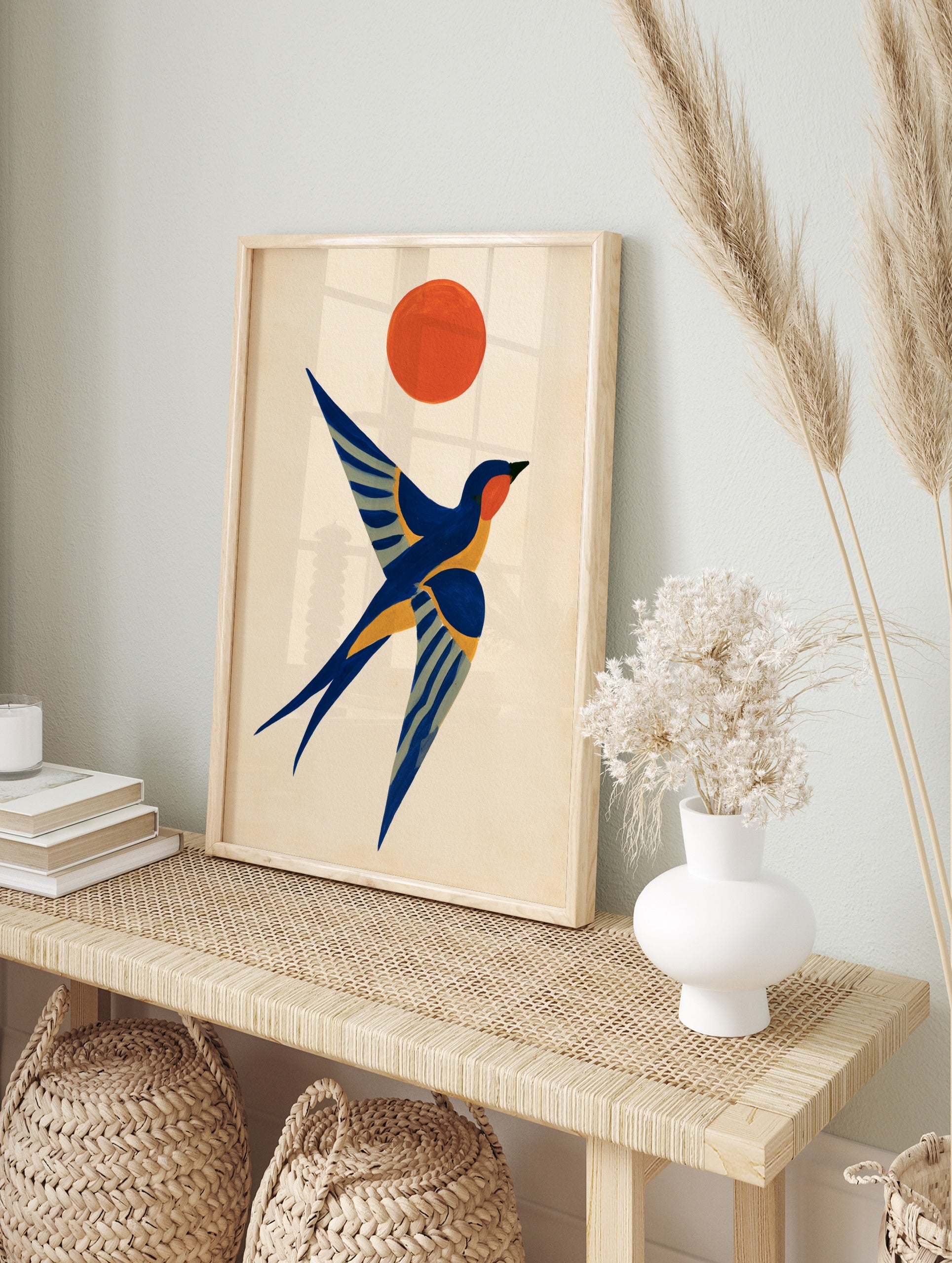 Stylised swallow bird in flight with an orange sun in a graphic, illustrative art style on a, in an alternate framed mockup