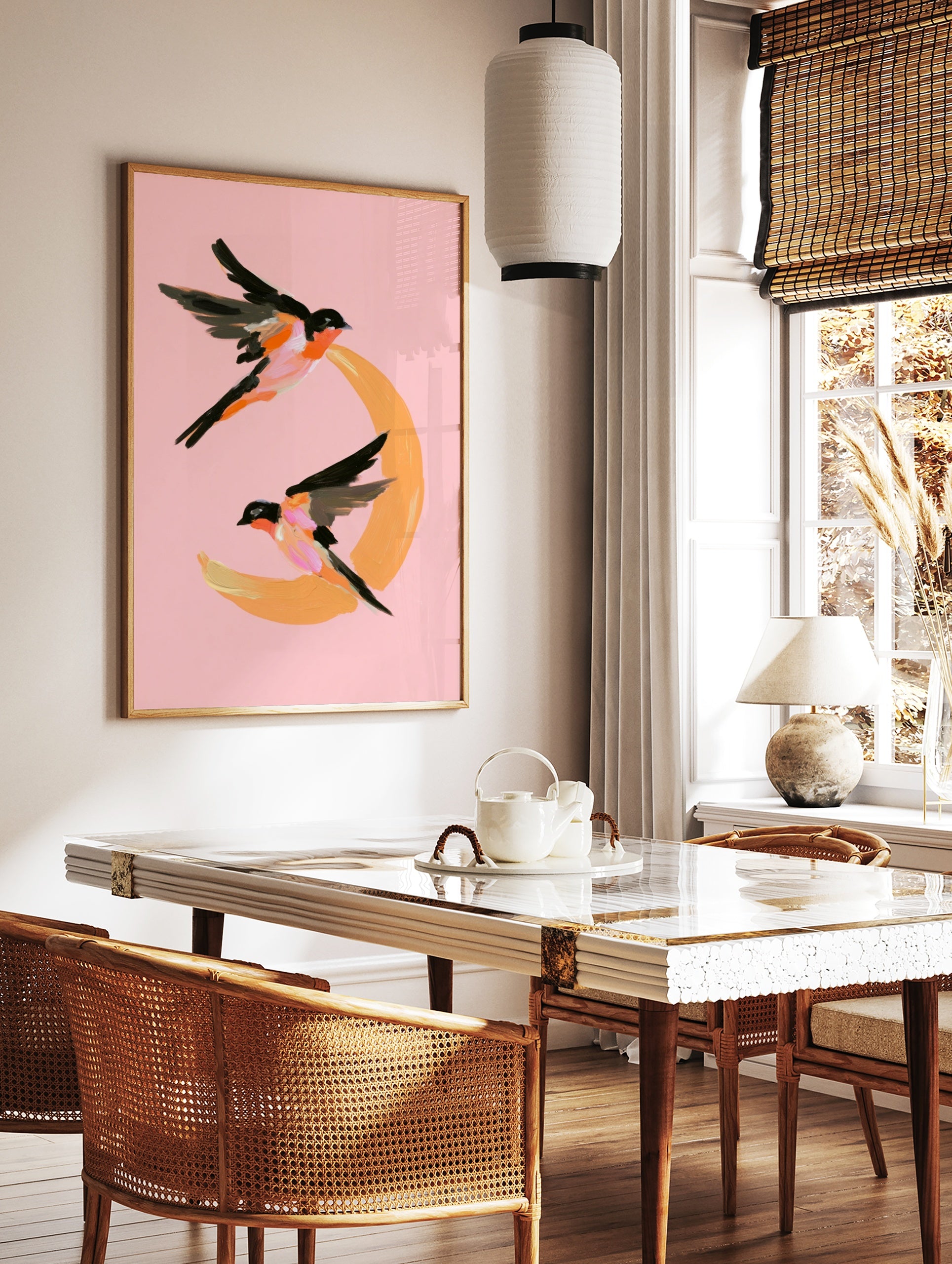 Painterly illustration of two swallows flying around an orange crescent moon on a pink background, in a styled room mockup