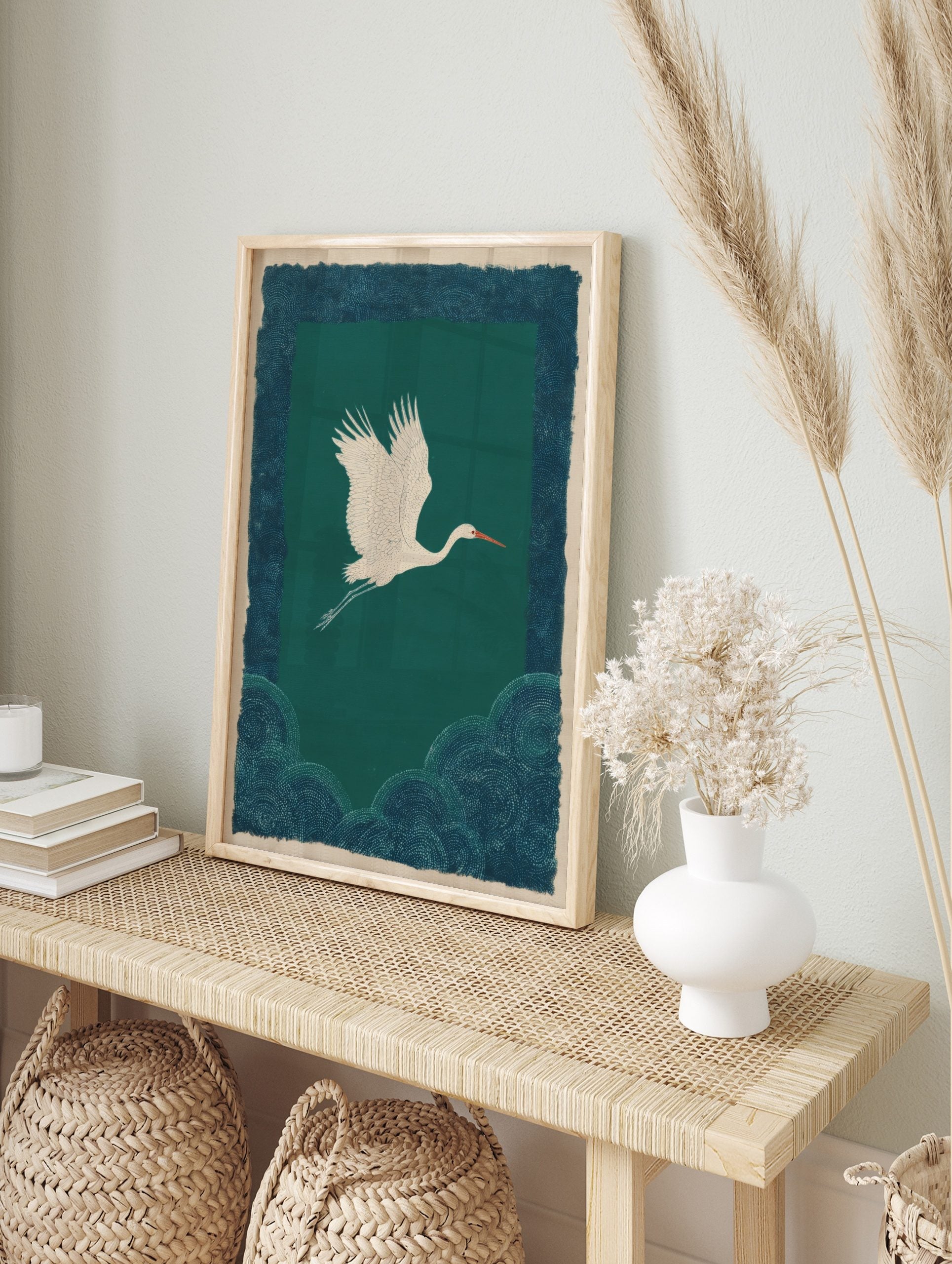 White crane flying over dark teal-green background with patterned blue-teal border and lower, in an alternate framed mockup
