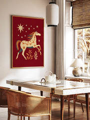 Folk art horse wall art print with orange dots, stars, and teal mane on a deep red background with, in a styled room mockup