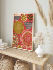 Folk art print of ornate plates, striped bowls, a lemon slice, and a plant on a red striped, in an alternate framed mockup