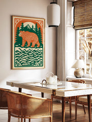 Illustrative forest bear print with orange bear, green pine trees, mountains, and cream water on a, in a styled room mockup