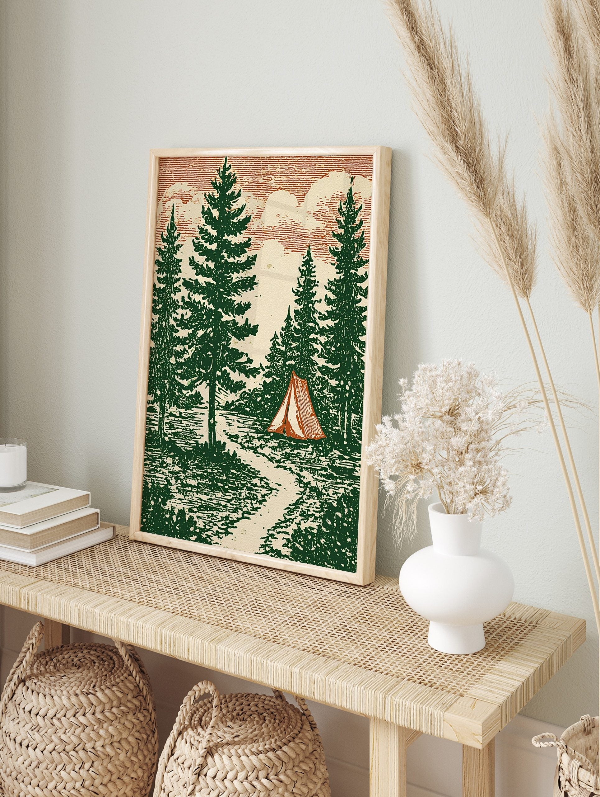 Illustrative forest scene with tall pine trees, a red and cream striped tent, a path, and a, in an alternate framed mockup