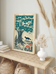 Woodcut style print of a teal fox walking past a large oak tree and red toadstools in a, in an alternate framed mockup