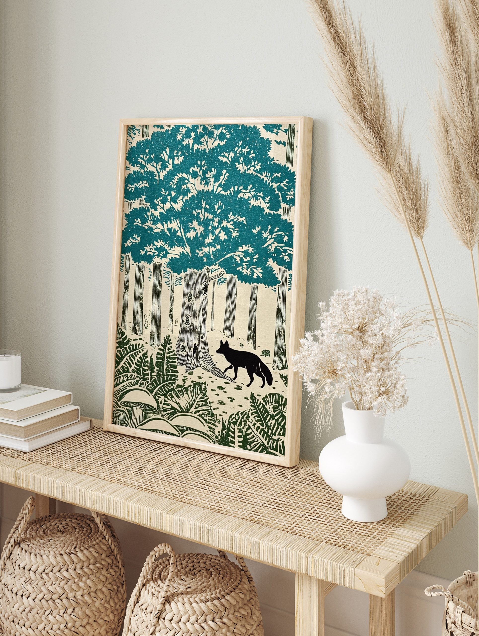 Woodcut style forest print with a black fox, large teal tree canopy, tree trunks, ferns, and, in an alternate framed mockup
