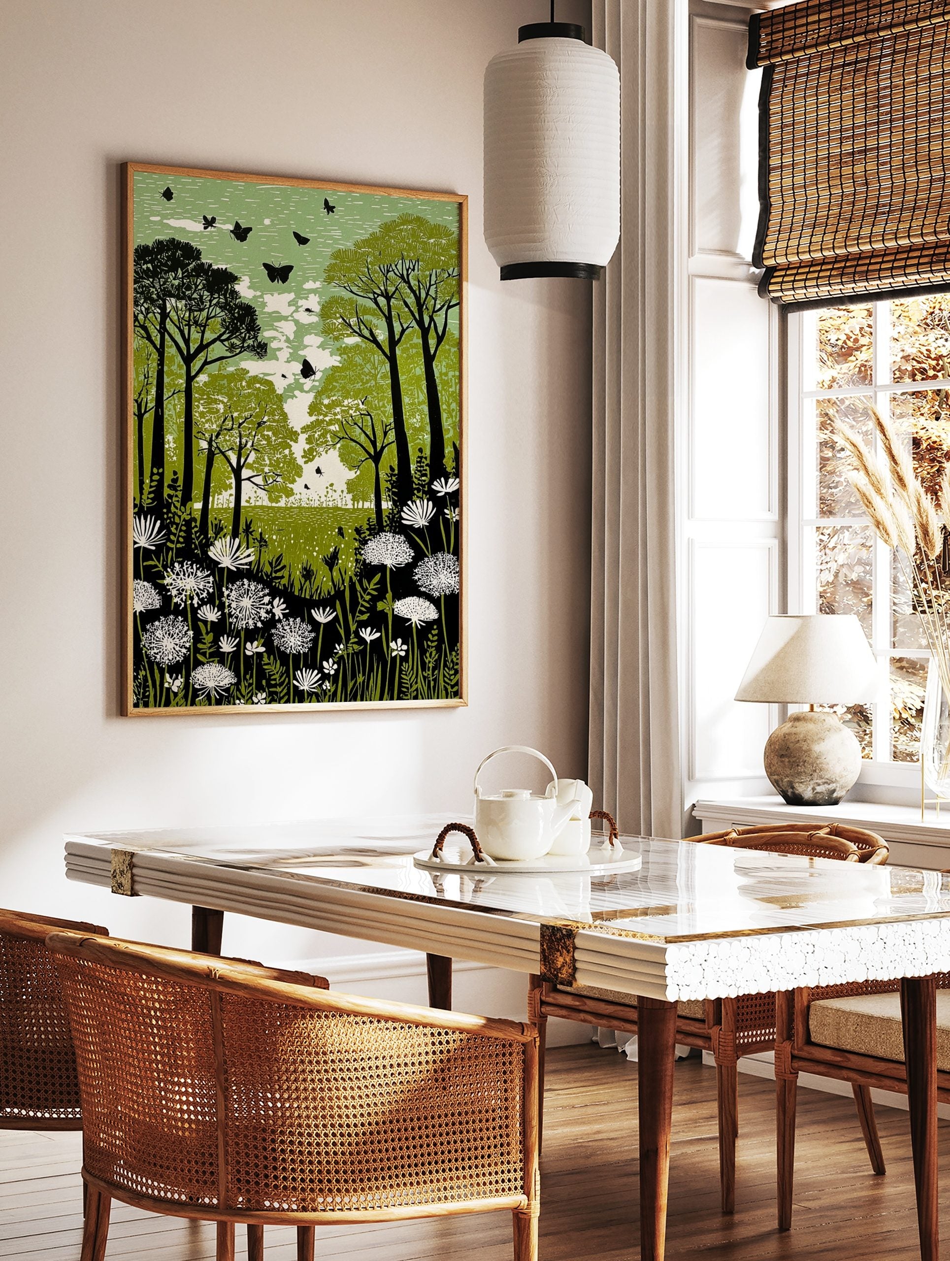 Green forest meadow print with dark trees, white flowers, and black butterflies in a linocut style, in a styled room mockup